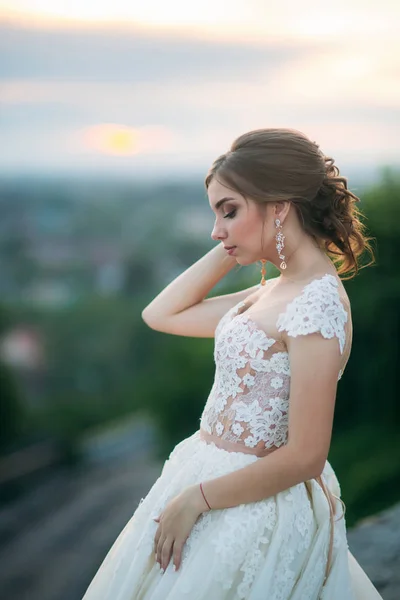 Rapariga em vestido de noiva no fundo da cidade ao pôr do sol. Verão — Fotografia de Stock