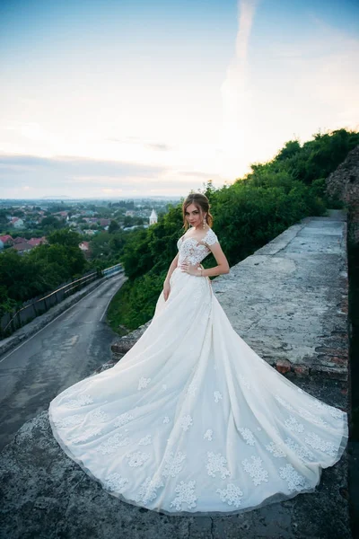 Chica joven en vestido de novia en el fondo de la ciudad al atardecer. Verano — Foto de Stock