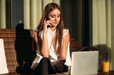 Genç kız çalışmak için bir tablet ve telefon kullanın. Kafede kız gülümsüyor