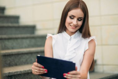 Genç kız çalışmak için bir tablet ve telefon kullanın. Kafede kız gülümsüyor