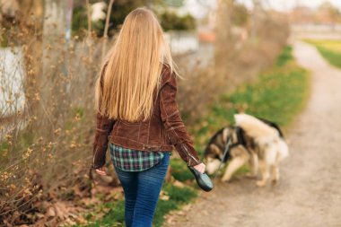 Güzel bir kız set yürüyor. Sarı saçlı ve kahverengi ceket.