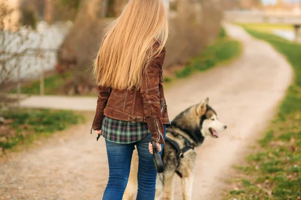 Une belle fille marche le long du remblai. Blond cheveux et veste brune . — Photo