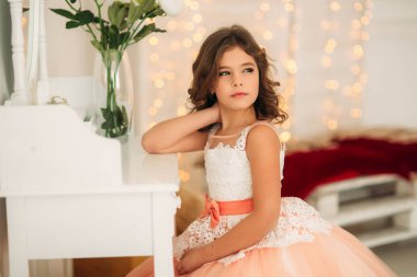 Güzel kız bir şeftali renkli elbiseli kahverengi saçlı. Bir fotoğrafçı için pozlar