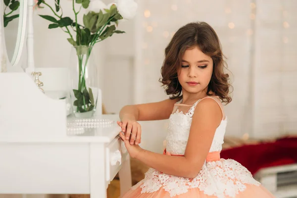 Menina bonita pequena com cabelo castanho em um vestido de cor de pêssego. Poses para um fotógrafo — Fotografia de Stock