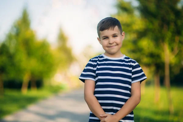 Ragazzino in t-shirt a righe guarda attraverso binocoli. Primavera, tempo soleggiato . — Foto Stock