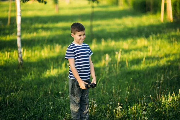 Niño con una camiseta a rayas mira a través de los prismáticos. . — Foto de Stock