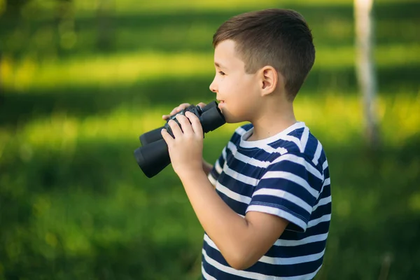 Niño con una camiseta a rayas mira a través de los prismáticos. . — Foto de Stock