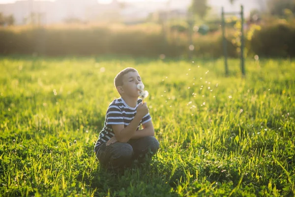 Un niño pequeño con una camiseta a rayas está jugando en el patio de recreo, columpio en un columpio. El niño está sonriendo y vitoreando — Foto de Stock