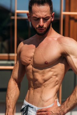 Genç atlet ile bir gövde bir tuğla duvar arka plan fotoğraf için poz. Kurtarma vücut geliştirmeci, atlet pompalanır kaslar, göğüs ve kol ile