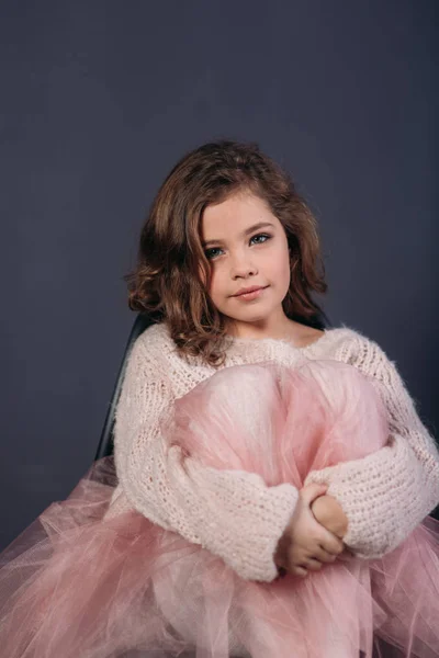 Mooi meisje met bruin haar in een lichte trui en een rok van tulle. Studio. Een prinses met zich meebrengt voor een fotograaf. — Stockfoto