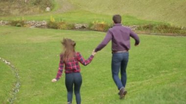 Sevgi dolu bir çift sonbaharda parkta yürüyor. Güneşli bir sonbahar gününde bir aşk hikayesi. göl ve bringe .