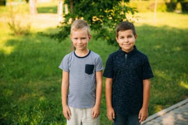 Çocuklar parkta oynuyorlar. İki güzel çocuk T-shirt ve şort gülümseyen eğlenin. Dondurma yemek, sıçrama, çalıştırın. Yaz güneşli