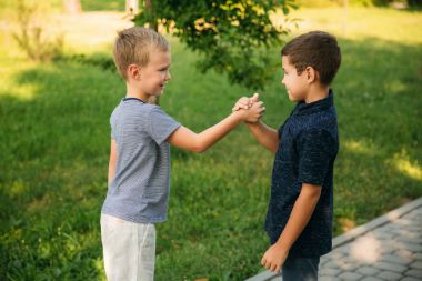 Çocuklar parkta oynuyorlar. İki güzel çocuk T-shirt ve şort gülümseyen eğlenin. Dondurma yemek, sıçrama, çalıştırın. Yaz güneşli