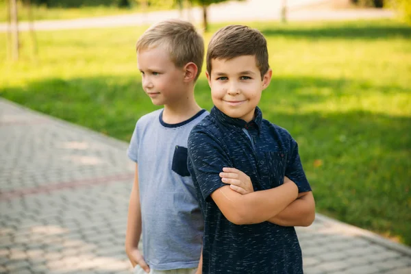 Çocuklar parkta oynuyorlar. İki güzel çocuk T-shirt ve şort gülümseyen eğlenin. Dondurma yemek, sıçrama, çalıştırın. Yaz güneşli