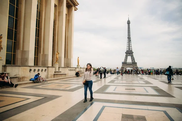 Gyönyörű lány pózol, hogy a fotós, a háttérben az Eiffel-torony. Őszi photosession. Napos idő. Szép mosoly és smink — Stock Fotó