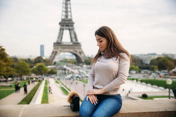 Gyönyörű lány pózol, hogy a fotós, a háttérben az Eiffel-torony. Őszi photosession. Napos idő. Szép mosoly és smink — Stock Fotó