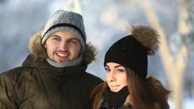 Genç bir adam ve bir kız sıcak kış elbiseleri giymiş zevk birbirlerinin huzurunda karlı bir kış parkı