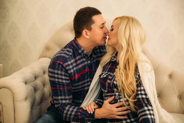 Happy couple in holiday spirit showing affection for one another. Dressed in plaid clothes. Gentle pregnant woman.