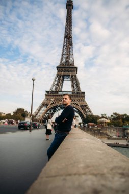Koyu mavi bir ceket giyen genç bir adam Eyfel Kulesi arka plan üzerinde duruyor. Güneşli havalarda Sonbahar geldi
