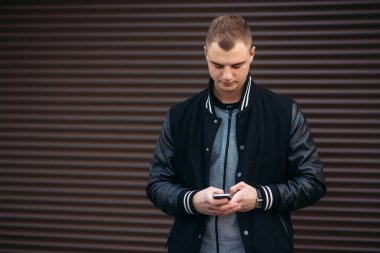 Bir arka plan koyu çizgili duvar siyah ceketli genç bir çocuk telefon kullanır