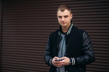 Bir arka plan koyu çizgili duvar siyah ceketli genç bir çocuk telefon kullanır