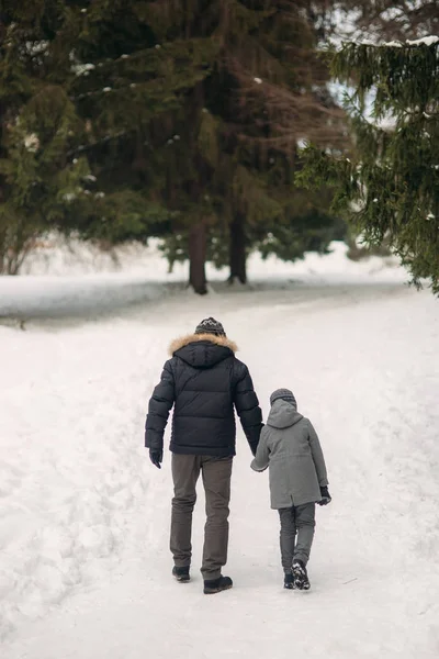 Pai feliz com seu filho caminha pelo parque no inverno nevado — Fotografia de Stock