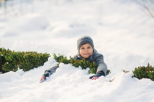 Um menino de roupas de inverno salta para a neve . — Fotografia de Stock