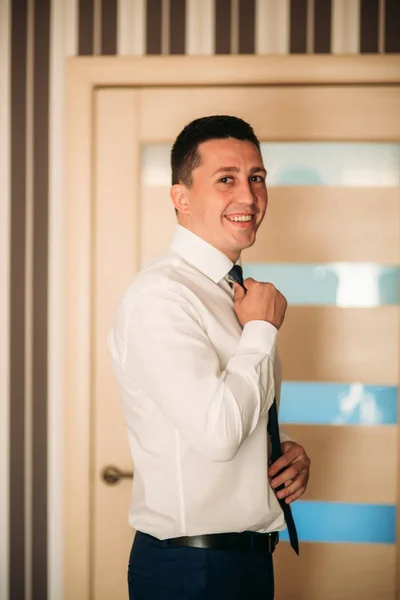 El novio está vestido de traje en casa. Lindo novio posando para un fotógrafo — Foto de Stock