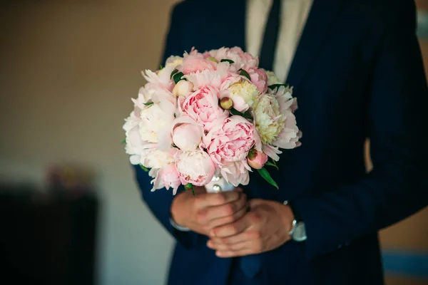 Zieht der mutige Bräutigam seinen Hochzeitsanzug an. Er hält einen Strauß in der Hand. Hochzeitstag — Stockfoto