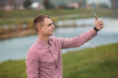 Bir telefonu kullanarak bir Kareli gömlekli şık adam