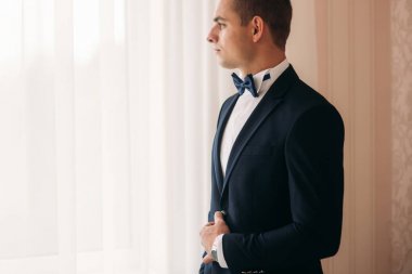 Damat takım elbiseli evde giyindi. Şirin damat bir fotoğrafçısına poz