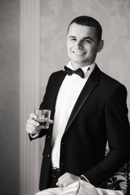 Damat takım elbiseli evde giyindi. Şirin damat bir fotoğrafçı için poz. Siyah ve beyaz