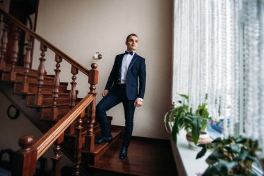 Damat takım elbiseli evde giyindi. Şirin damat bir fotoğrafçısına poz