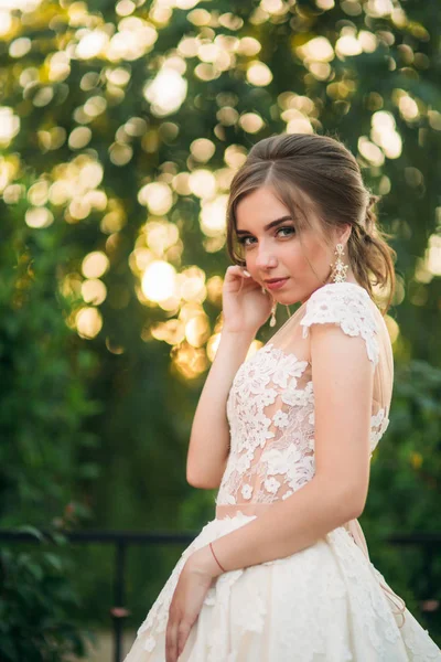 Jovem em vestido de noiva no parque posando para fotógrafo. Tempo ensolarado, verão — Fotografia de Stock