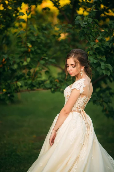 Jovem em vestido de noiva no parque posando para fotógrafo. Tempo ensolarado, verão — Fotografia de Stock