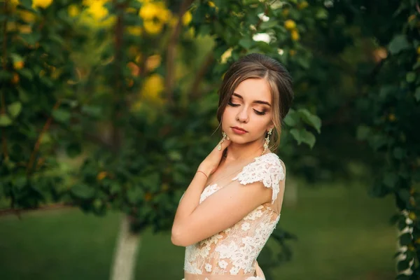 Junges Mädchen im Hochzeitskleid im Park posiert für Fotografen. Sonnenwetter, Sommer — Stockfoto