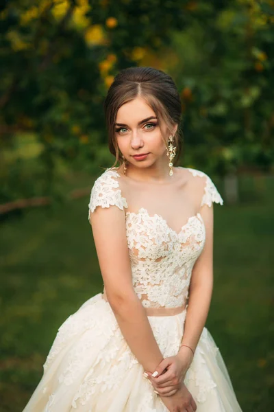 Chica joven en vestido de novia en el parque posando para el fotógrafo. Tiempo soleado, verano —  Fotos de Stock