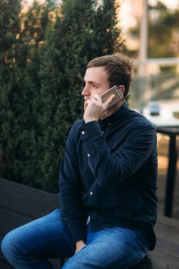 Genç bir adamın cep telefonundan konuşuyor. İş