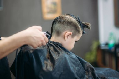 Çocuğun saçlarını Kuaför içinde bir sandalyede oturur