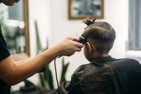 Niño en un corte de pelo en el barbero se sienta en una silla — Foto de Stock