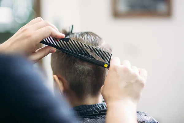 Niño en un corte de pelo en el barbero se sienta en una silla — Foto de Stock