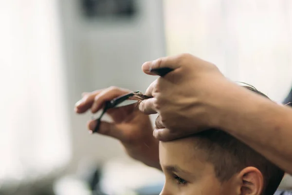 Chłopak coraz fryzura przez nożyczek w fryzjera. Fryzjer użyć nożyczek — Zdjęcie stockowe