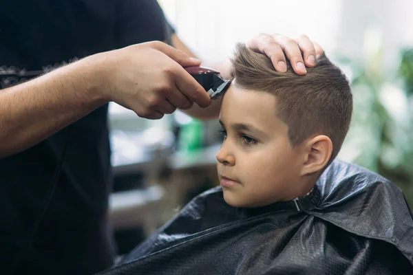 Професійний перукар використовує затискач для стрижки волосся для маленького хлопчика — стокове фото
