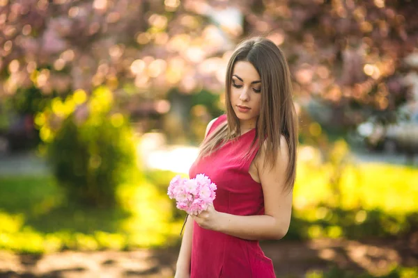 Belle fille posant au photographe sur fond de fleurs d'arbres roses. Le printemps. Sakura — Photo