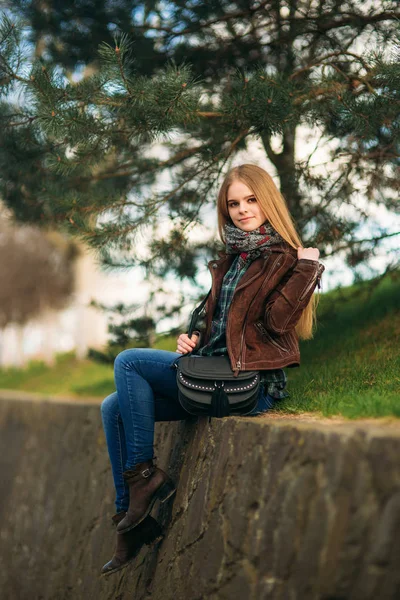 Een mooi meisje is een wandeling langs de kade. Blond haar en bruine jas. Lente — Stockfoto