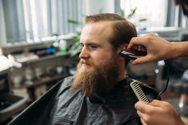 Sakallı adam bir saç kesimi saç kesme makineleri ile sahip