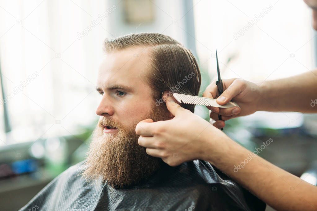 Barber using scissors and comb in barbershop