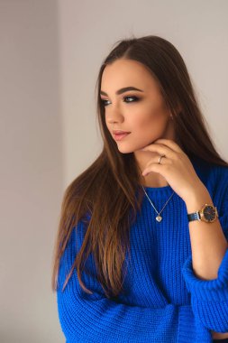 Güzel esmer kız mavi bir bluz bir fotoğrafçısına poz ve ona makyaj gösteren güzel bir gülümseme