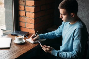 Çalışma ve bir şey not defterinde bir kafe ve yazma kahve içme iş adamı