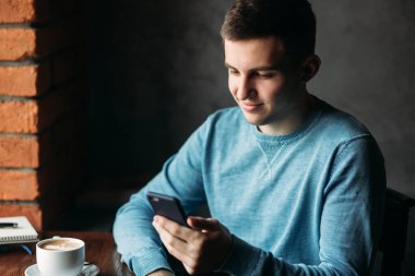 Adam bir kafede telefonuyla pencerenin oturur